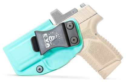 CYA teal blue Base IWB holster with a black belt clip on a tan fn reflex handgun